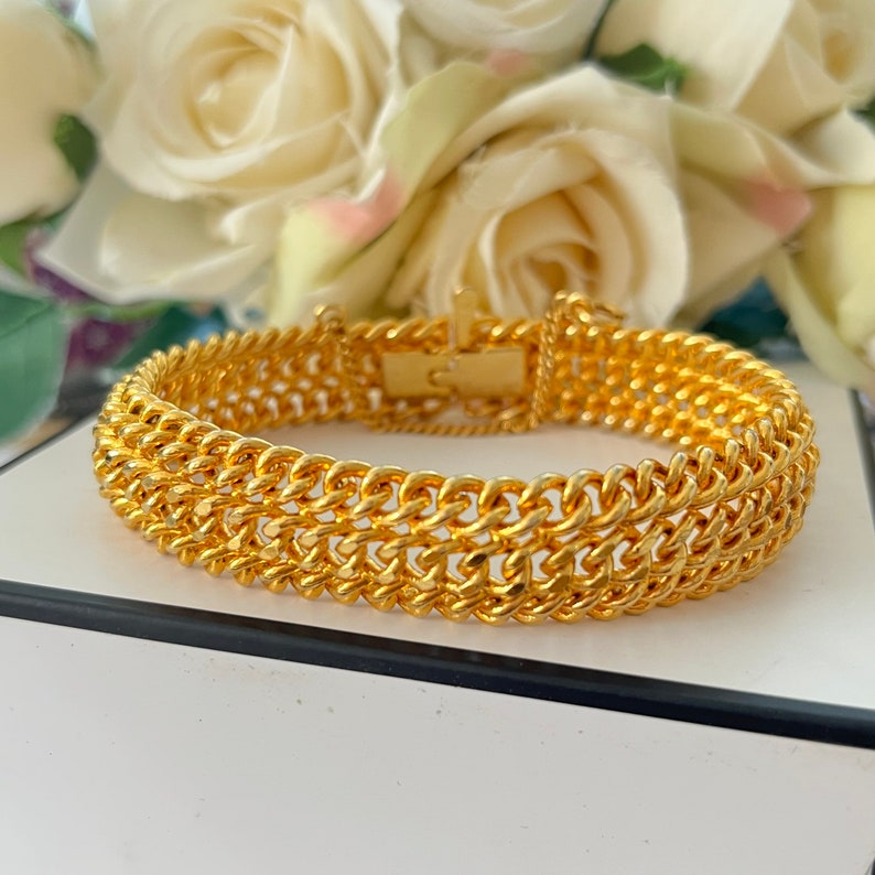 Puede incluir: Un brazalete de cadena de oro con una doble fila de eslabones entrelazados. El brazalete tiene un cierre de broche.