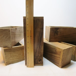May include: Set of six wooden boxes, stacked and arranged in a staggered formation. The boxes are made of natural wood with a rustic finish. The boxes are various sizes and are perfect for storage or display.