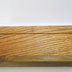 May include: A wooden display stand with a natural wood finish. The stand is made of two pieces of wood that are joined together with a small gap between them. The stand is perfect for displaying small items, such as jewelry, crafts, or other small objects.