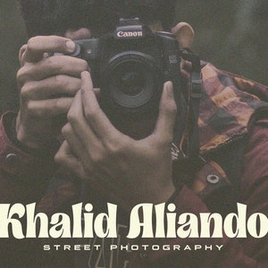 May include: A person holding a Canon camera, with the text "Khalid Alliando STREET PHOTOGRAPHY" below.