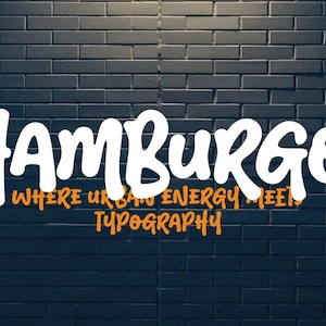 May include: White "Hamburgo" text in a bold, rounded font, with orange text below that reads "Where urban energy meets typography." The text is set against a dark blue brick wall background.