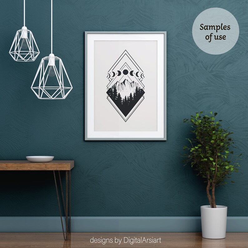 May include: A framed black and white art print featuring a mountain and forest scene with moon phases. The artwork is displayed on a teal wall. The image also shows a wooden table, a potted plant, and two geometric pendant lights.