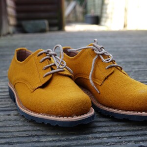 May include: A pair of mustard yellow leather lace-up shoes with brown soles.