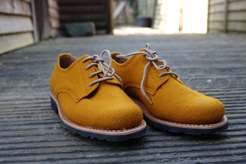 May include: A pair of mustard yellow leather lace-up shoes with brown soles.