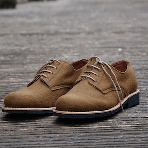 May include: A pair of brown suede lace-up shoes with a black rubber sole.