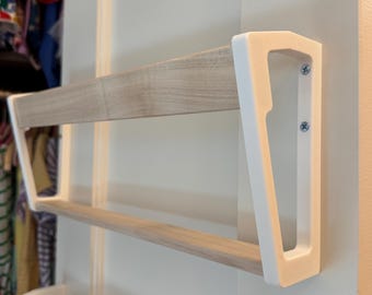 May include: A two-tiered wall-mounted shelf with a light wood grain finish and white supports. The shelf is attached to a white wall with screws. The design is modern and minimalist, suitable for displaying items or storage.