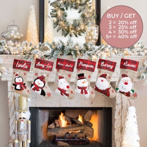 Peut inclure: Six chaussettes de Noël personnalisées en tissu de jute avec une bordure en tartan rouge. Chaque chaussette présente un motif brodé différent, notamment un pingouin, un renne, un bonhomme de neige et le Père Noël. Les chaussettes sont accrochées à une cheminée avec une figurine de casse-noisette en dessous.