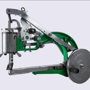 Pode incluir: Máquina de costura industrial resistente, prateada e verde. A máquina possui um grande volante, uma agulha e vários componentes mecânicos. Projetada para costurar materiais espessos.