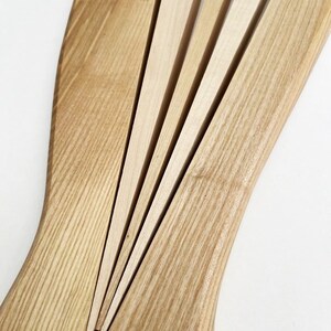 May include: A wooden salad serving set with a fan-shaped design. The set is made of light brown wood and has a natural finish.