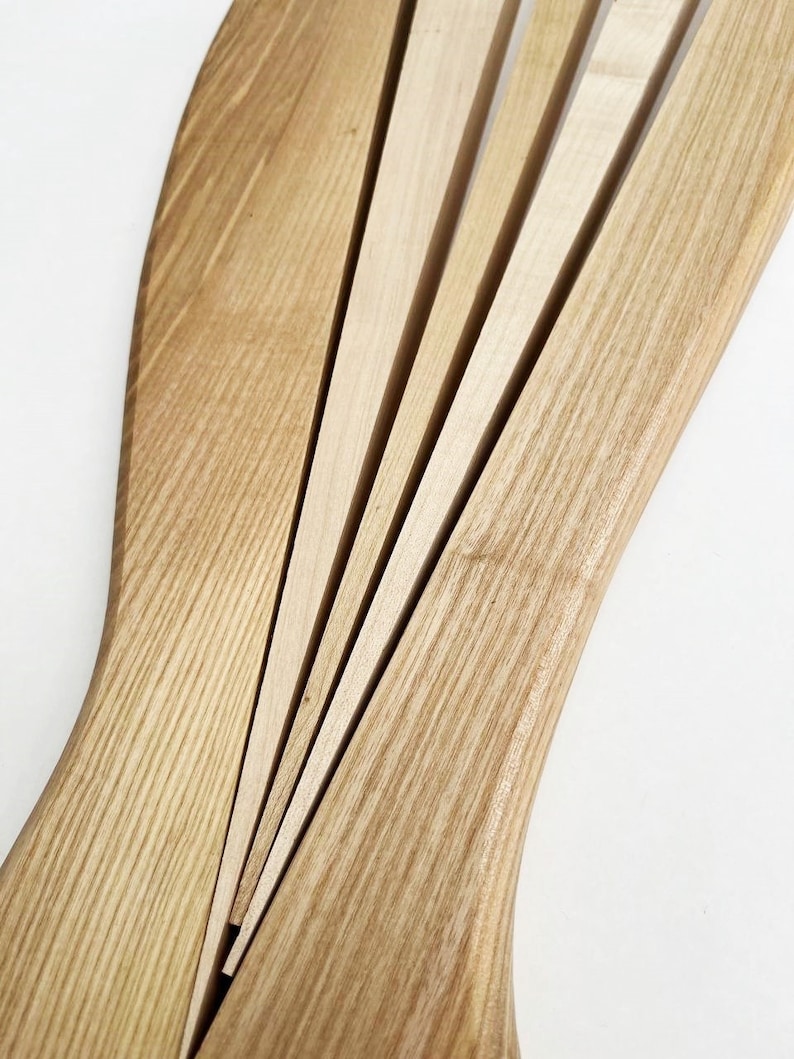 May include: A wooden salad serving set with a fan-shaped design. The set is made of light brown wood and has a natural finish.