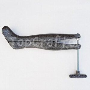 May include: A gray shoe stretcher with a metal screw and a T-shaped handle. The stretcher is designed to help stretch shoes to a wider fit.