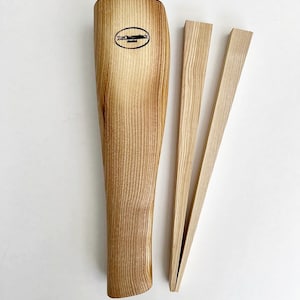 May include: Wooden kitchen tongs with a natural wood finish. The tongs are made of two long, thin pieces of wood that are joined together at the top. The tongs are designed to be used for picking up and holding food.