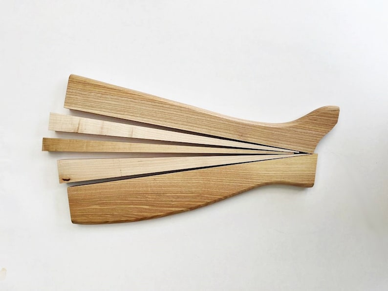 May include: A wooden salad serving set with a long, curved handle and five thin, wooden blades that fan out from the handle.