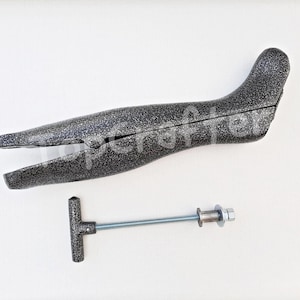 May include: A gray plastic boot stretcher with a metal screw and handle. The stretcher is designed to help stretch out boots to make them more comfortable.