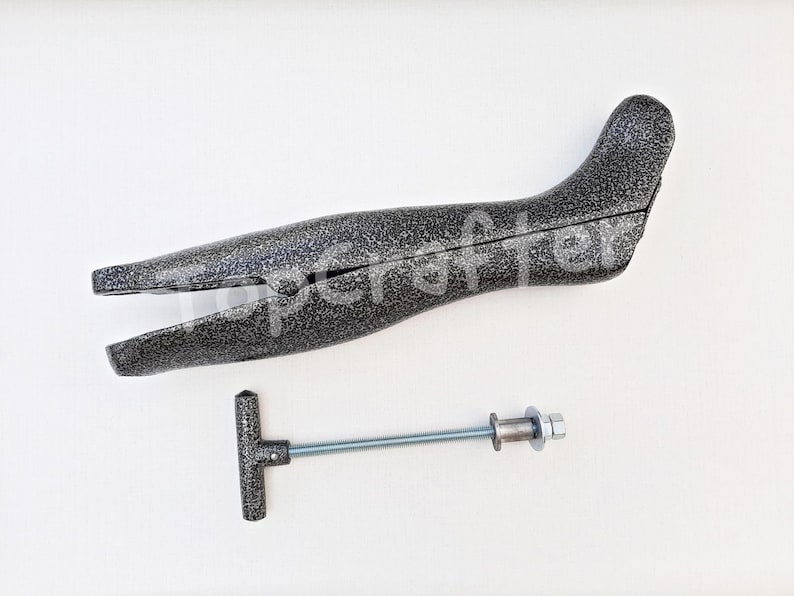 May include: A gray plastic boot stretcher with a metal screw and handle. The stretcher is designed to help stretch out boots to make them more comfortable.