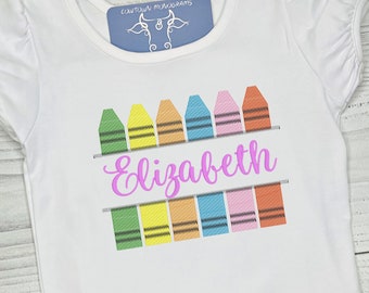 Könnte beinhalten: Weißes T-Shirt mit einer Reihe von bunten, kreidenförmigen Designs und dem Namen "Elizabeth", der in Rosa gestickt ist.