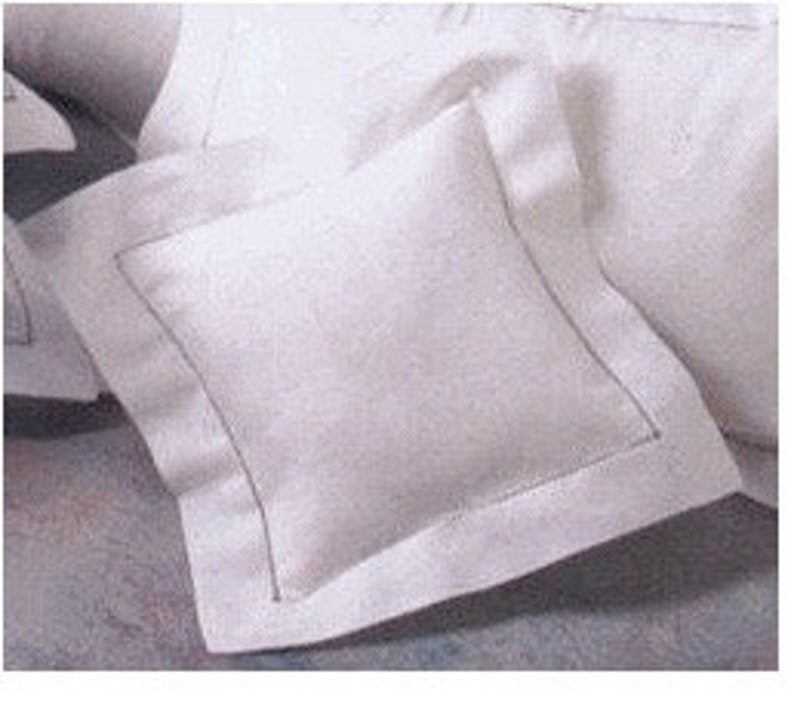Puede incluir: Almohada cuadrada blanca con un borde en contraste y costuras visibles. La almohada est&aacute; hecha de una tela suave y texturizada y forma parte de un juego de cama. El dise&ntilde;o es simple y elegante, adecuado para varios estilos de dormitorio.