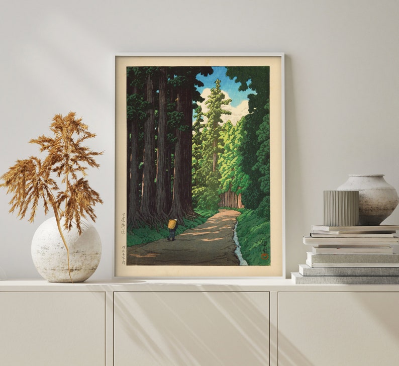 May include: A vintage woodblock print depicting a path through a forest of tall trees. The path leads to a clearing with a single figure walking away from the viewer. The print is framed in a white frame.