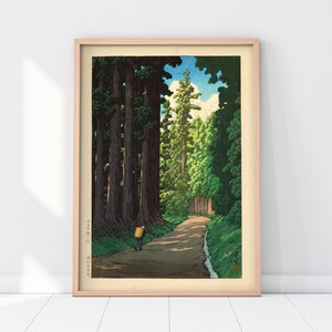 May include: A woodblock print depicting a path through a forest of tall trees. The path is lined with trees on both sides, and a single figure walks along the path. The sky is blue with a few white clouds. The print is framed in a light wood frame.