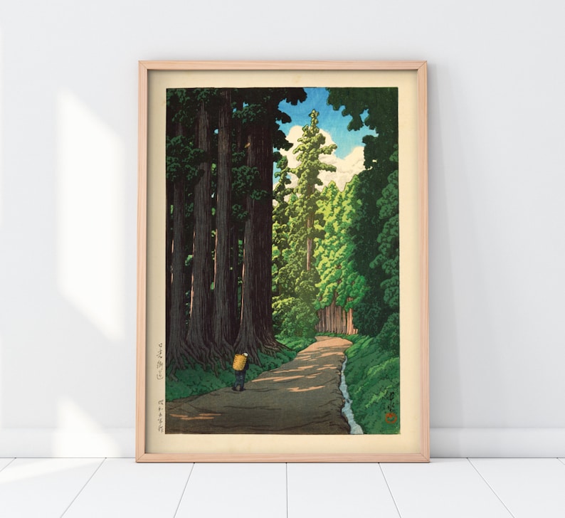 May include: A woodblock print depicting a path through a forest of tall trees. The path is lined with trees on both sides, and a single figure walks along the path. The sky is blue with a few white clouds. The print is framed in a light wood frame.