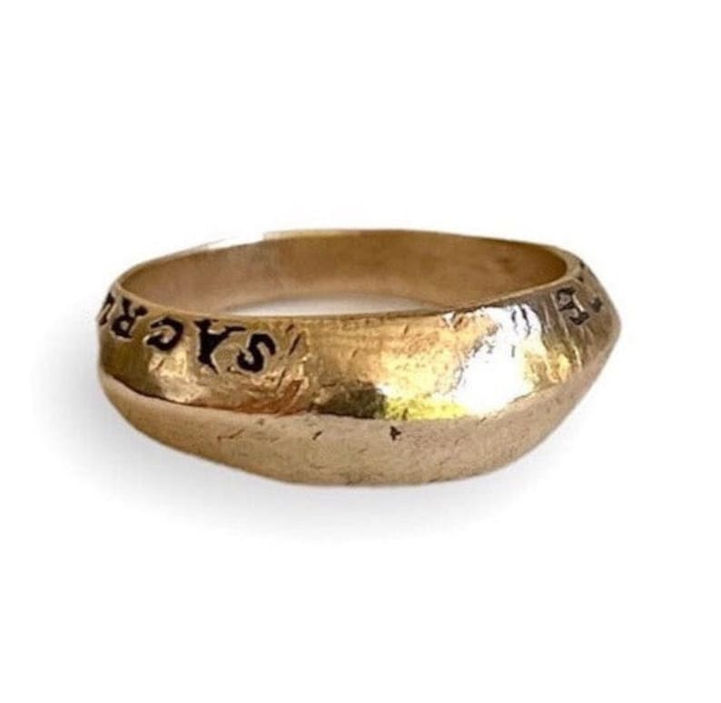 May include: A gold ring with the inscription "SAGR" engraved on the band.