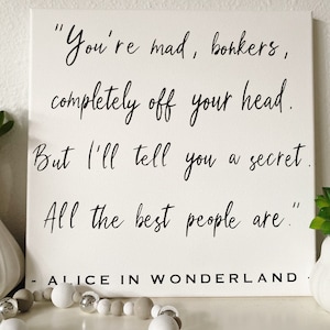 May include: A white canvas with black text that reads "You're mad, bonkers, completely off your head. But I'll tell you a secret. All the best people are." - ALICE IN WONDERLAND.
