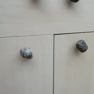 Puede incluir: Dos puertas de armario blancas con pomos de piedra. Los pomos de piedra son de diferentes formas y colores.