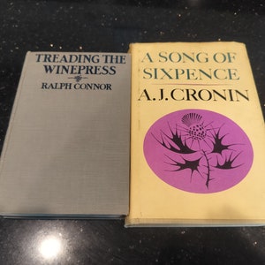 May include: Two paperback books, one with a gray cover and the title "Treading the Winepress" by Ralph Connor, and the other with a yellow cover and the title "A Song of Sixpence" by A.J. Cronin.