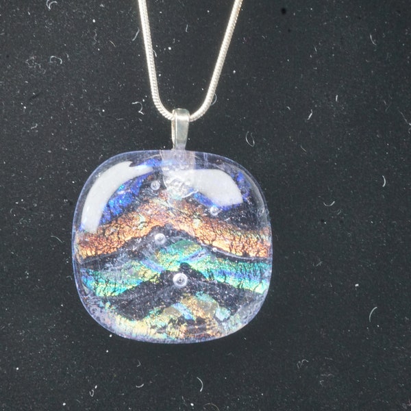 Beautiful small Pendant. This pendant is filled with Gold, Lt Blue, Dark Blue, and Red strips of dichroic glass. Then capped in clear glass.