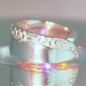 May include: A silver ring with a floral design. The ring is made from a recycled spoon and has a unique, handcrafted look.