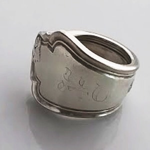 Könnte beinhalten: Silberlöffelring mit einer personalisierten Inschrift. Die Inschrift lautet "S.J. 2-10-70".