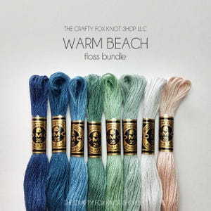 May include: A set of six embroidery floss spools in shades of blue, green, and beige. The spools are labeled "DMC" and "Mouline Special". The text "Warm Beach floss bundle" is printed above the spools.