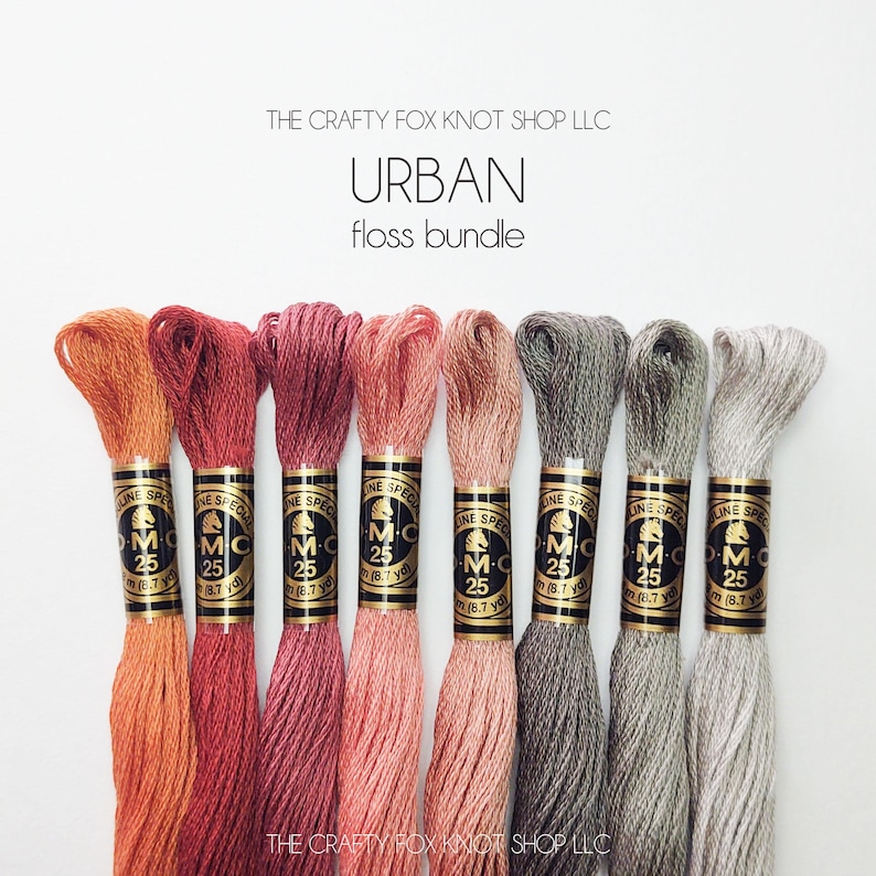 May include: A set of eight embroidery floss spools in shades of orange, red, pink, gray, and beige. The spools are labeled "DMC" and "Special" with the number "25". The text "The Crafty Fox Knot Shop LLC" and "Urban floss bundle" is printed above the spools.