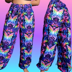 May include: Vibrant, psychedelic-style pants with a repeating butterfly pattern. The pants feature a drawstring waist and a loose, comfortable fit. The color palette includes blues, purples, pinks, and yellows, creating a colorful and eye-catching design.