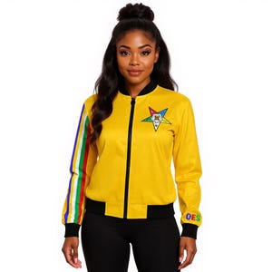 May include: Yellow bomber jacket with a black zipper and trim. The jacket features a colorful star emblem on the chest and a striped design on the left sleeve. The right sleeve has the letters "OES" in a colorful design.