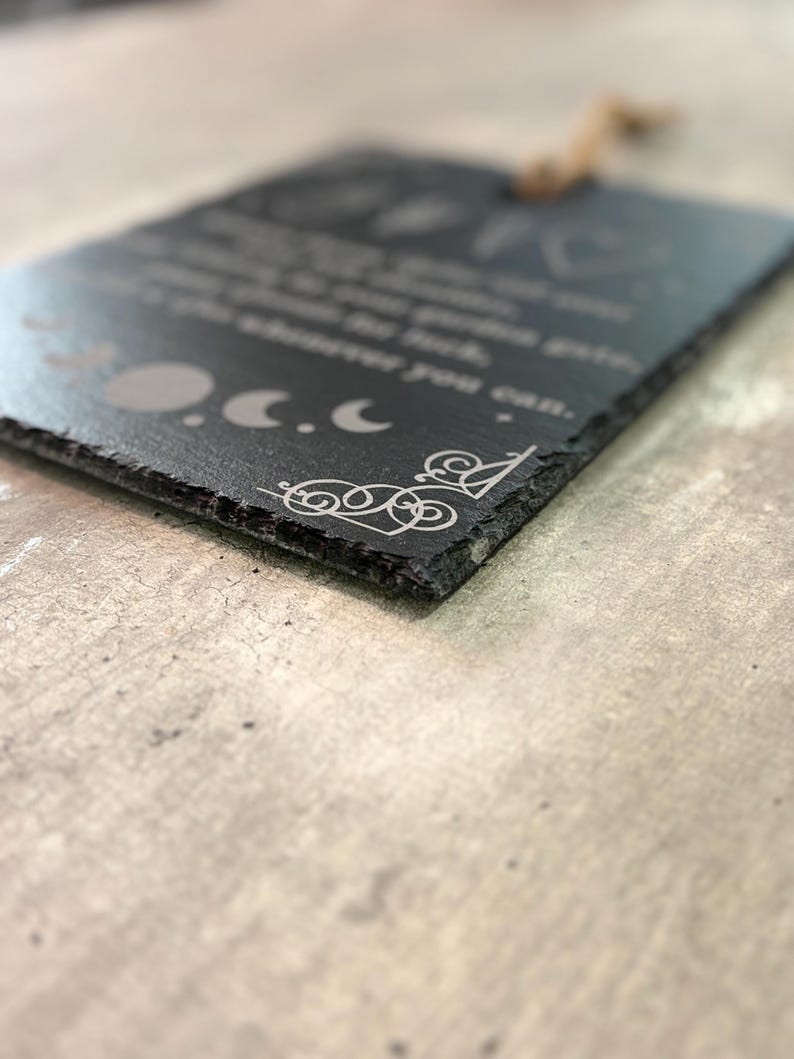 May include: Black slate sign with a white inscription that reads "You are braver than you think, stronger than you seem, and smarter than you believe.  You are loved more than you know.  You are capable of more than you imagine.  You are enough.  You are magic.  You are you.  And that is more than enough."  The sign also features a decorative design of three moons and a swirl.