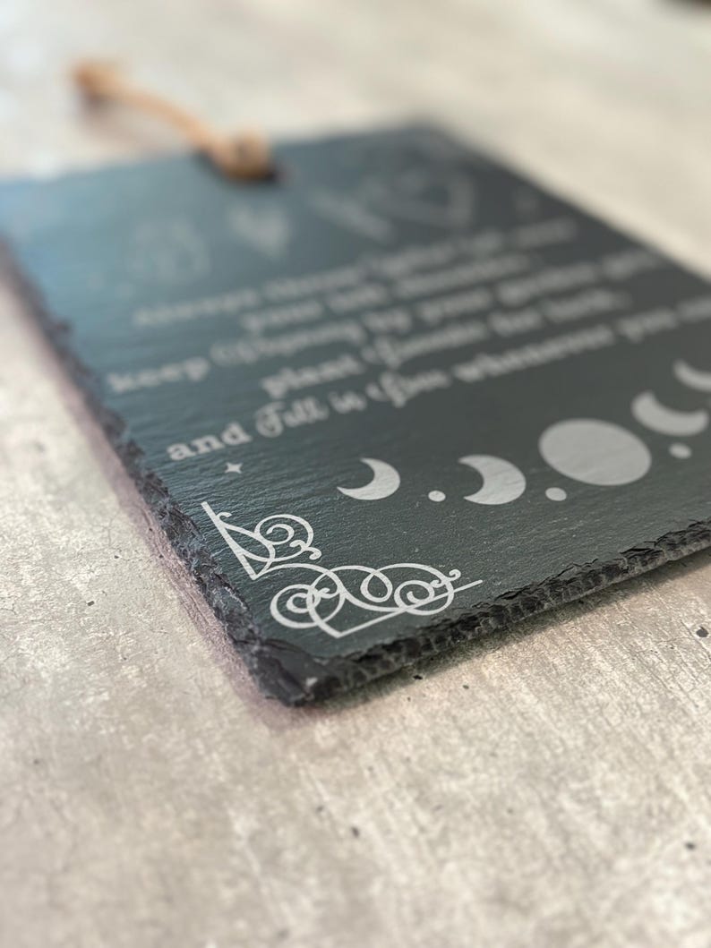 May include: Black slate sign with white text and moon phases. The text reads "Always trust your gut, keep chasing the moon, and fall in love wherever you go."