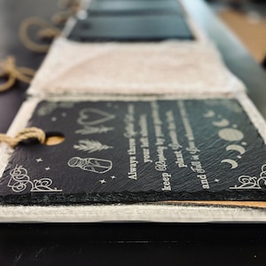 May include: A black slate sign with a white inscription that reads "Always there, your light shines brighter. Keep hoping, by your own plant, you grow and fall in your own time." The sign has a decorative border and a small jar with a lid, a heart, and a moon and stars.