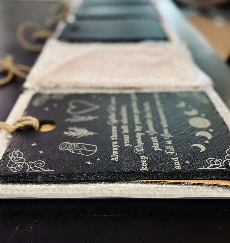 May include: A black slate sign with a white inscription that reads "Always there, your light shines brighter. Keep hoping, by your own plant, you grow and fall in your own time." The sign has a decorative border and a small jar with a lid, a heart, and a moon and stars.