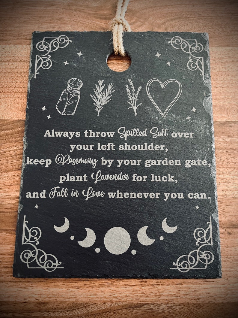 May include: Black slate sign with white text and illustrations. The text reads "Always throw Spilled Salt over your left shoulder, keep Rosemary by your garden gate, plant Lavender for luck, and Fall in Love whenever you can."