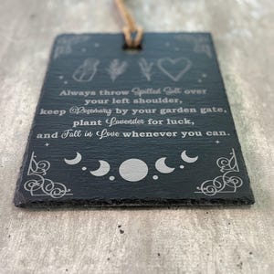 May include: Black slate sign with white text and illustrations. The text reads: "Always throw spilled salt over your left shoulder, keep rosemary by your garden gate, plant lavender for luck, and fall in love whenever you can."