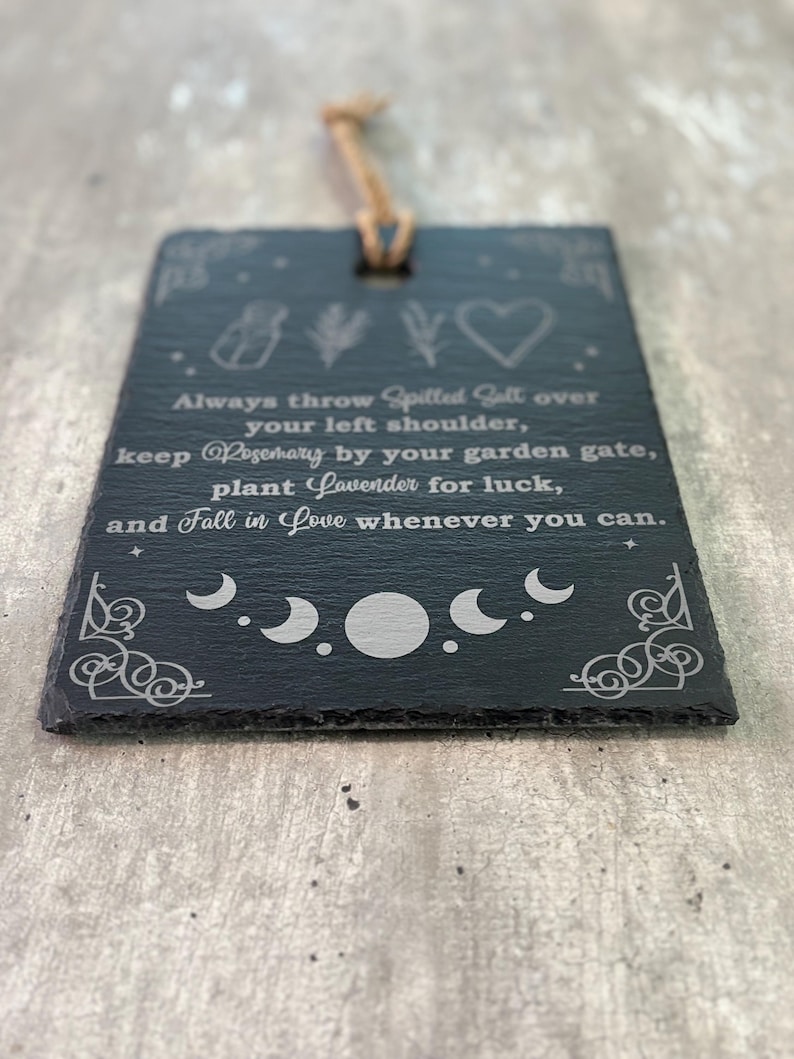 May include: Black slate sign with white text and illustrations. The text reads: "Always throw spilled salt over your left shoulder, keep rosemary by your garden gate, plant lavender for luck, and fall in love whenever you can."