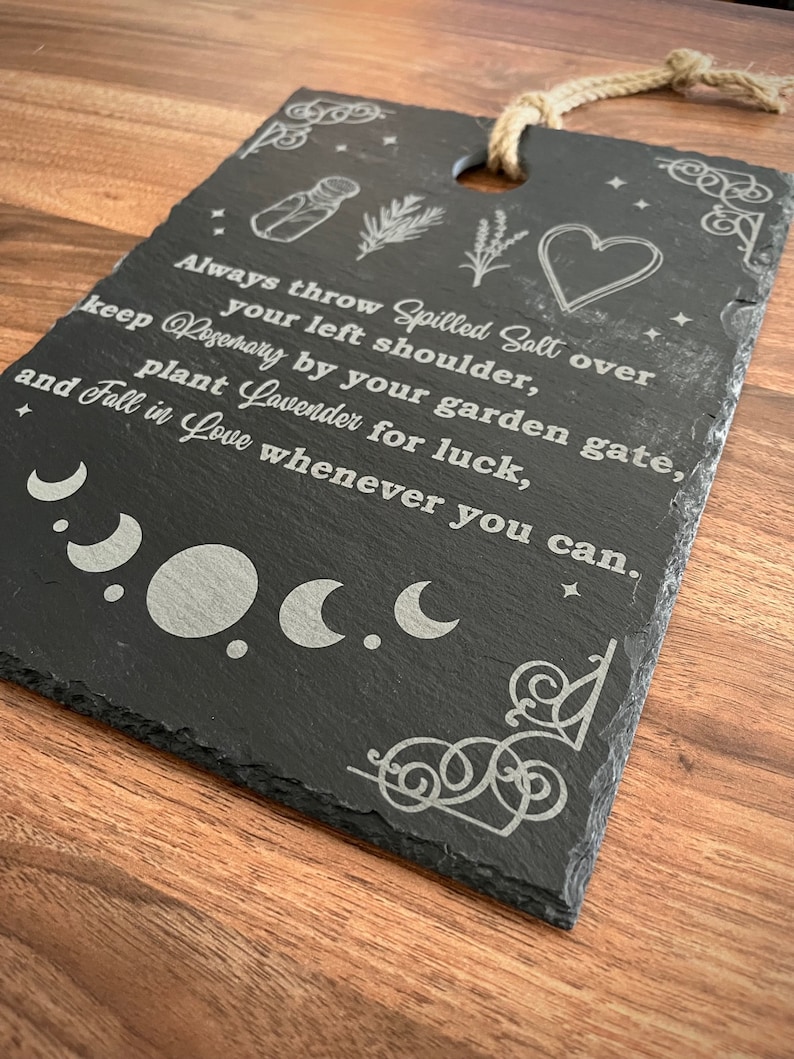 May include: Black slate sign with white text and illustrations. The text reads: "Always throw Spilled Salt over your left shoulder, keep Rosemary by your garden gate, plant Lavender for luck, and Fall in Love whenever you can."