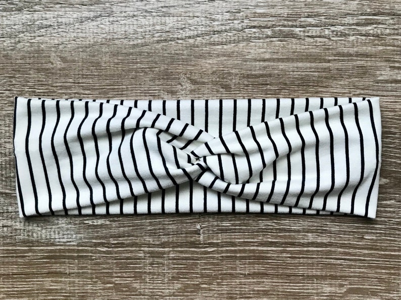 May include: A white and black striped headband with a twisted knot in the center.