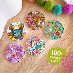 May include: A selection of circular magnets with floral and bee motifs. One magnet says "Thank You For Being An Amazing Teacher." Other magnets display vibrant flower patterns. The image also includes a green oval with the text "100+ Magnet Designs."