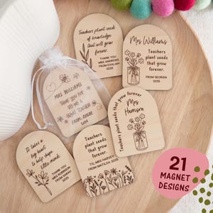 May include: A selection of wooden magnets with engraved designs and text. The magnets display floral motifs and quotes such as "Teachers plant seeds that grow forever." Some magnets are personalised with names and dates. A small bag of magnets is also present.