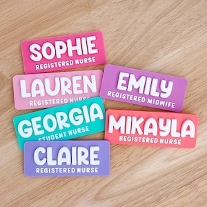 May include: A selection of name badges in various colours, including pink, purple, and teal. Each badge features a name in white raised lettering, such as SOPHIE and LAUREN, and a job title like "Registered Nurse" or "Student Nurse".