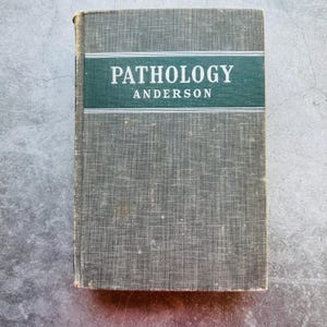 Könnte beinhalten: Ein Vintage-Hardcover-Buch mit einem grün-weißen Rücken. Der Titel "PATHOLOGY" ist in Weiß auf grünem Hintergrund gedruckt, darunter der Name des Autors "ANDERSON" in Weiß.