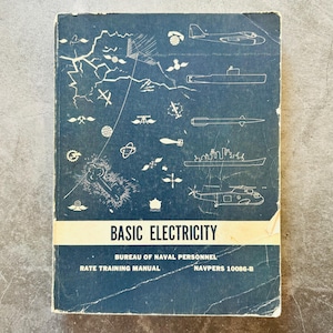 May include: A dark blue instructional manual titled Basic Electricity, Bureau of Naval Personnel, Rate Training Manual, NAVPERS 10086-B. The cover features white line drawings of military aircraft, ships, submarines, and electrical symbols.