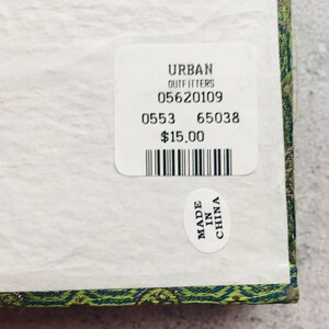 May include: A close-up of a white label from Urban Outfitters with the numbers 05620109, 0553, and 65038. A smaller sticker reads "MADE IN CHINA". The label is on a patterned surface.